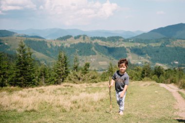 Küçük çocuk bir dağ köyünün yakınında yürüyor.