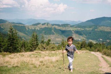 Küçük çocuk bir dağ köyünün yakınında yürüyor.