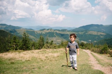 Küçük çocuk bir dağ köyünün yakınında yürüyor.