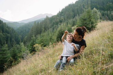 Genç anne ve küçük oğlu seyahat ediyorlar. Anne çocukla gezintiye çıktı, aile gezisi dağlarda. Ulusal Park. Çocuklarla yürüyüş. Aktif yaz tatili. Fisheye merceği