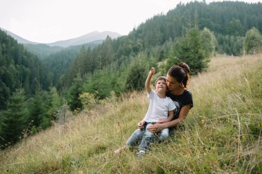 Genç anne ve küçük oğlu seyahat ediyorlar. Anne çocukla gezintiye çıktı, aile gezisi dağlarda. Ulusal Park. Çocuklarla yürüyüş. Aktif yaz tatili. Fisheye merceği