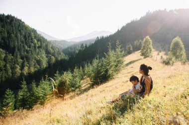 Genç anne ve küçük oğlu seyahat ediyorlar. Anne çocukla gezintiye çıktı, aile gezisi dağlarda. Ulusal Park. Çocuklarla yürüyüş. Aktif yaz tatili. Fisheye merceği