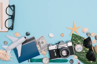 Seyahat konsepti, saat, uçak, para, pasaport, kalem, kitap, fotoğraf çerçevesi, mavi arkaplanda fotokopi alanı olan gözlük hazırlığı.