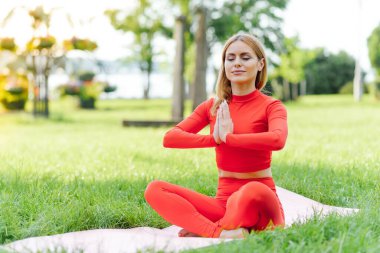 Parkta yoga egzersizi yapan güzel bir kadın.