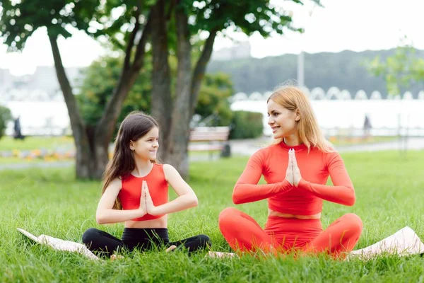 母と娘は公園で芝生の上でヨガの練習をしています — ストック写真