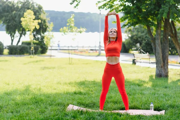 緑の公園でヨガの練習をしている若い女性 — ストック写真