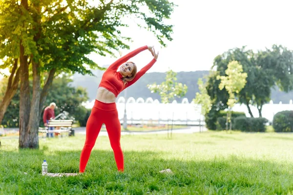 公園でフィットネストレーニングセッションの前に若い女性のワークアウト 健康的な若い女性が屋外で温暖化 腕を伸ばして目を離そうとしてる — ストック写真