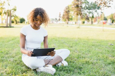 Dokunsal tablet kullanan gülümseyen zenci bir kızın açık hava portresi. Afrikalı insanlar.
