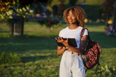 Çevrimiçi iletişim, eğitim veya iş kavramı. Parkta tablet bilgisayarı olan güzel Afrikalı Amerikalı bayan.