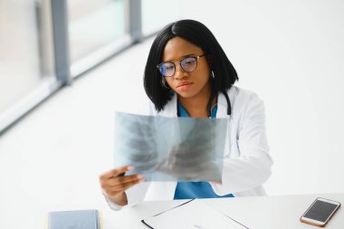 Genç, Afro-Amerikan doktor hastaların göğüs röntgenlerini inceliyor.