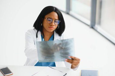 Genç, Afro-Amerikan doktor hastaların göğüs röntgenlerini inceliyor.