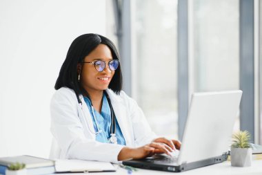 Afro-Amerikan mutlu gülümseyen genç doktor portresi. Kulaklık takan hasta telefonda. Çevrimiçi sağlık merkezi kavramı