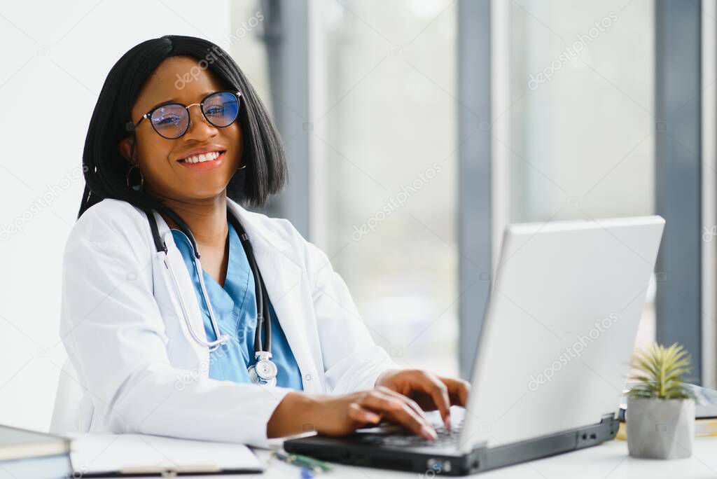 Young African-American doctor working on laptop in clinic