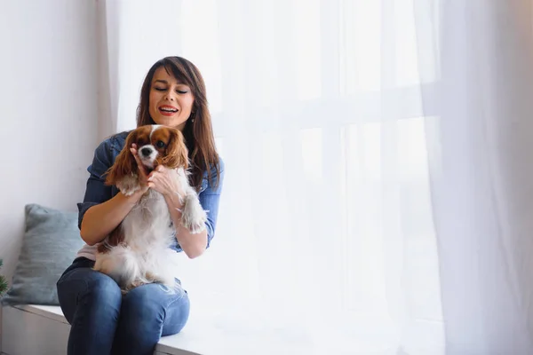 Mujer Sonriente Abrazando Lindo Perro Mirando Por Ventana — Foto de Stock