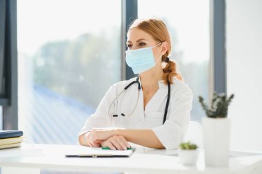 Coronavirus 2019 hastalığı veya COVID-19 küresel salgınından korunmak için hastane maskesi takan bir doktor..