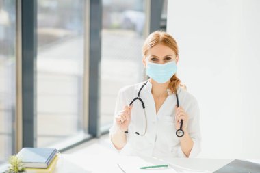 Coronavirus 2019 hastalığı veya COVID-19 küresel salgınından korunmak için hastane maskesi takan bir doktor..