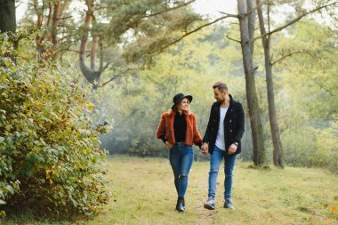 Aşıklar sonbahar parkında el ele yürür