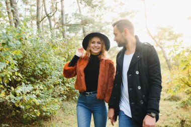 Aşıklar sonbahar parkında el ele yürür