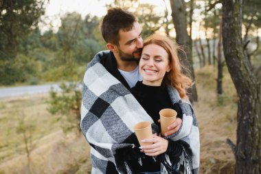 Genç ve romantik bir çift nazikçe sarılıp, kendilerini ekoseyle ısıtıyorlar. Romantik aşk ilişkileri kavramı.