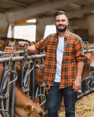 İnek ahırının yanında duran genç bir çiftçinin portresi. Arka planda saman yiyen Jersey sığırlarıyla gülümsüyor.