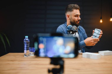 Canlı yayın sırasında yeni cep telefonu özelliklerini sunan erkek etkili, teknoloji meraklısı izleyiciler için ilgi çekici içerik yaratıyor