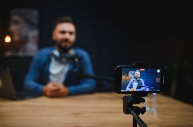 İyi donanımlı bir ev stüdyo ortamında akıllı telefon ve mikrofon kullanırken içeriği yakalayan video blogcusu