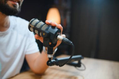 Ev stüdyosunda profesyonel mikrofon kullanarak podcast için ses içeriğini kaydeden video blogcusu