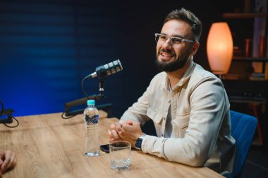 İçerik yaratıcısı, ses içeriği aracılığıyla izleyicilerle bağlantı kurarak, profesyonel bir stüdyoda podcast bölümü kaydediyor.