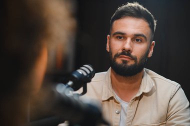 Profesyonel bir stüdyoda podcast kaydeden iki içerik yaratıcısı, sohbete dalıp uzmanlıklarını paylaşıyorlar.