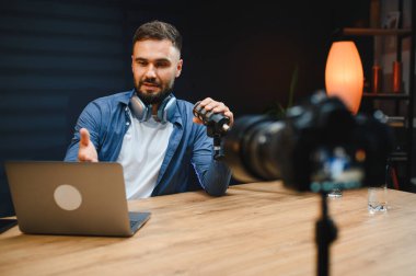 İçerik oluşturucu profesyonel bir mikrofon, kulaklık, dizüstü bilgisayar ve kamera kullanarak bir video blogu kaydediyor.