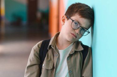 Okulun koridorunda duvara yaslanmış, ağlayan ve sınıf arkadaşlarının zorbalığının ağırlığını hisseden üzgün bir öğrenci derin duygusal sıkıntı yaşıyor.