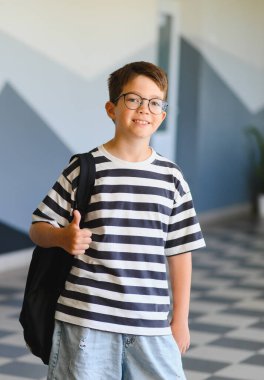 Neşeli bir öğrencinin portresi, olumlu bir jest yapıyor, okul çevresi ve kendine güveni ifade ediyor.