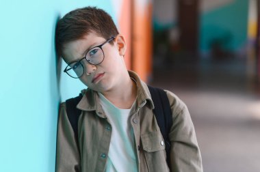 Okulun koridorunda duvara yaslanmış üzgün bir öğrenci. Ağlıyor ve sınıf arkadaşlarının zorbalığından bunalıyor. Derin duygusal acı çekiyor.