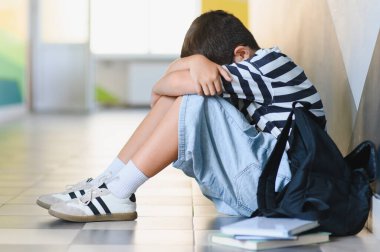 Okul koridorunda tek başına ağlayan üzgün öğrenci, zorbalığın acısını yaşıyor ve yalnızlığın ve umutsuzluğun ağırlığını hissediyor.