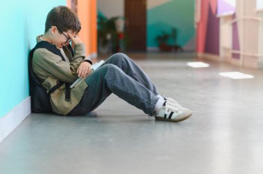 Okulun koridorunda tek başına ağlayan üzgün öğrenci, sınıf arkadaşlarının zorbalık ve şiddeti kurbanı.