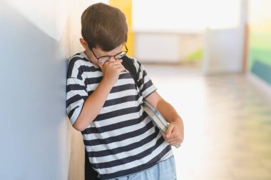 İlkokul öğrencisi okul koridorunda ağlarken ve gözyaşlarını silerken sınıf arkadaşlarının zorbalığına maruz kaldıktan sonra üzgün ve yalnız hissediyordu.