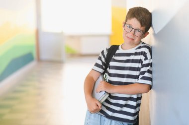 Okulun koridorunda duvara yaslanmış, zorbalıktan ve sınıf arkadaşlarından uzak kalmaktan dolayı ağlayan üzgün bir öğrenci.