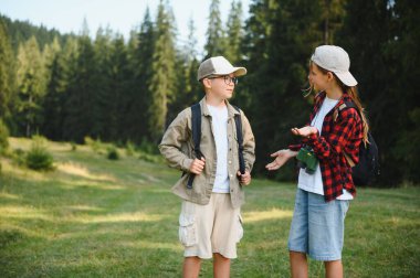 Sırt çantalı iki genç turist ormanda yürüyüş yapıyor, doğayı keşfediyor ve yaz tatillerinde eğleniyorlar.