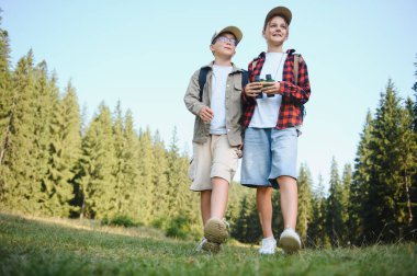 Sırt çantalı iki genç turist güneşli bir günde ormanda yürüyüş yaparak eğleniyorlar.