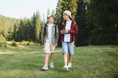 İki genç izci yaz tatilinin tadını çıkarıyorlar, yemyeşil bir ormanda yürüyüş yapıyorlar, sırt çantaları ve dürbünle, maceraya hazırlar.