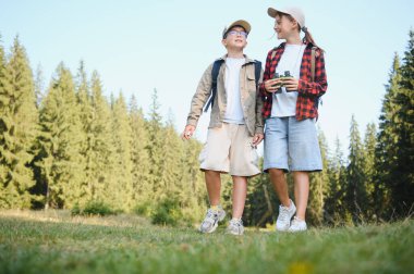 İki genç izci, ellerinde dürbünle yemyeşil bir ormanda gezintiye çıkmışlar. Macera ve keşfe hazırlar.