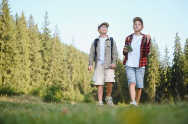 Sırt çantalı iki genç yürüyüşçü yemyeşil bir ormanda doğa keşfi yapıyor ve maceraya hazır.