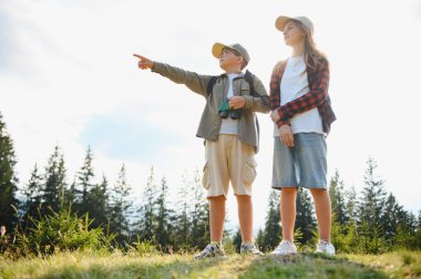 İki genç izci bir ormanı keşfederken, çocuk elinde dürbünle ilginç bir şeyi işaret ederek açık hava maceralarının tadını çıkarıyor.