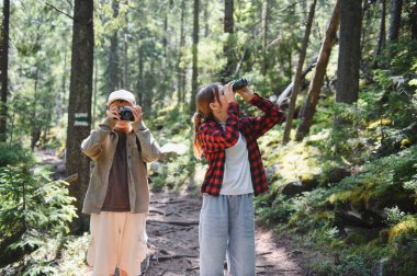 İki genç turist yemyeşil bir ormanda gezintilerinin tadını çıkarıyorlar, bir kamerayla anılarını yakalıyorlar ve dürbünle vahşi yaşamı izliyorlar.
