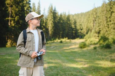 Çocuk izci yaz tatili maceraları sırasında yemyeşil bir ormanda yürürken eski bir kamerayla anıları yakalıyor.