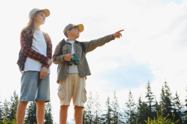 Çocuklar yaz tatilinden zevk alıyor, doğayı keşfediyor, dürbünle vahşi hayatı inceliyor, ilginç bir şeyi işaret ediyor.