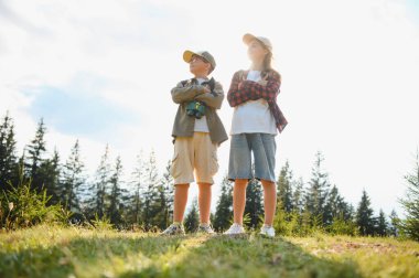 İki genç izci gururla ormanı temizliyor, doğanın güzelliği arasında macera ve keşif ruhunu kucaklıyor.