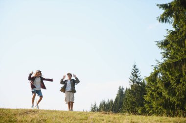 İki genç turist dağlarda yürüyüş yapıyor, yaz tatillerinin tadını çıkarıyor ve mutluluklarını dile getiriyorlar.