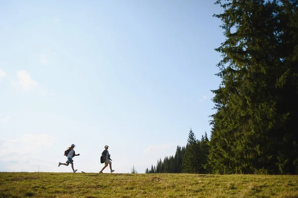 İki genç yürüyüşçü, doğanın güzelliğini kucaklayarak güzel bir dağ manzarasında yolculuklarının tadını çıkarıyorlar.