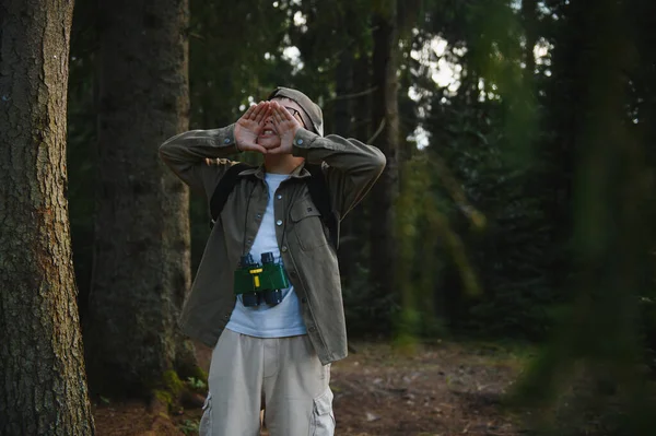 Dürbün ve sırt çantası takan genç izci yoğun bir ormanda kaybolduktan sonra yardım için bağırıyor.